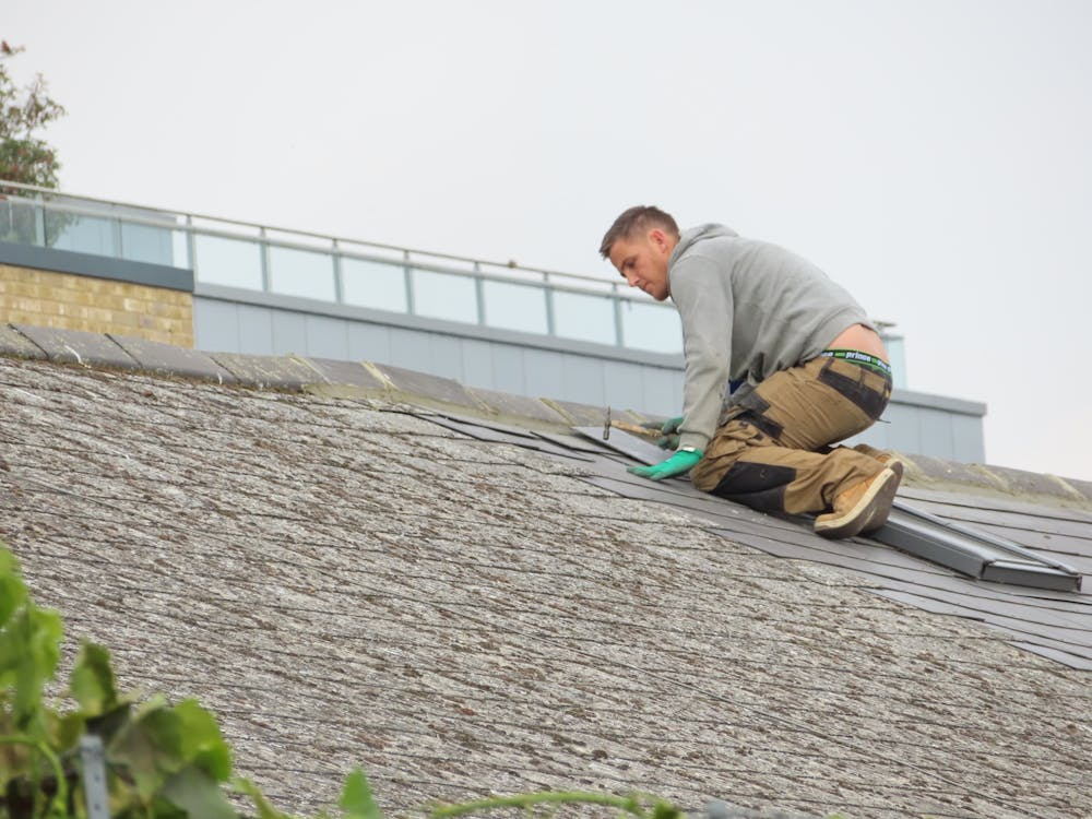 An expert and certified roofer working on the repair of a residential roof. Get in touch with us today to receive your free estimate.