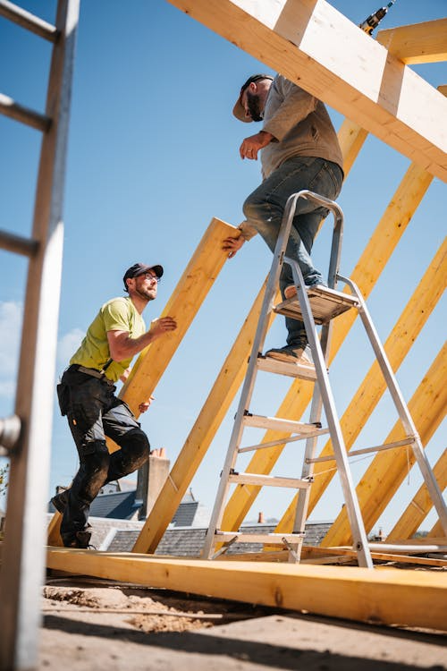 Experienced roofers working on the installation of a wooden rooftop. Get your free estimate today by contacting us.