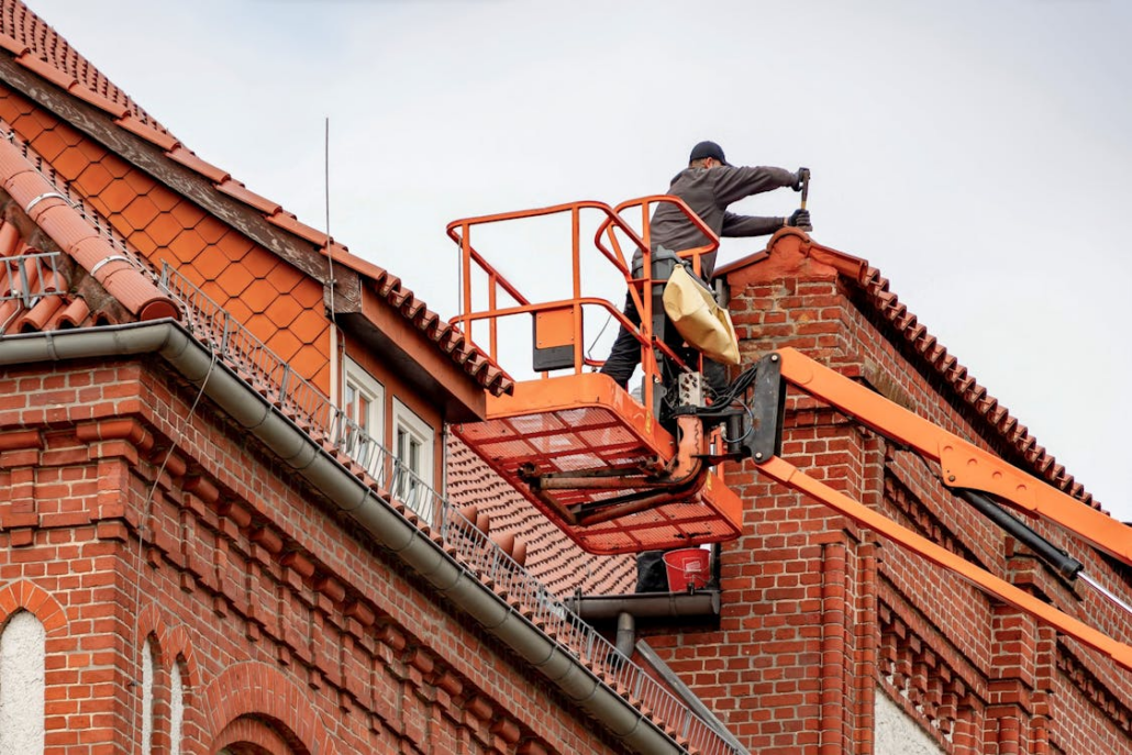 An experienced roofer performing maintenance on a red brick building. Reach out to us today and get your free estimate.