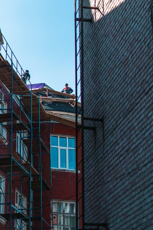 Certified roofing contractors working on a building rooftop. Get in touch with us today for your free estimate.